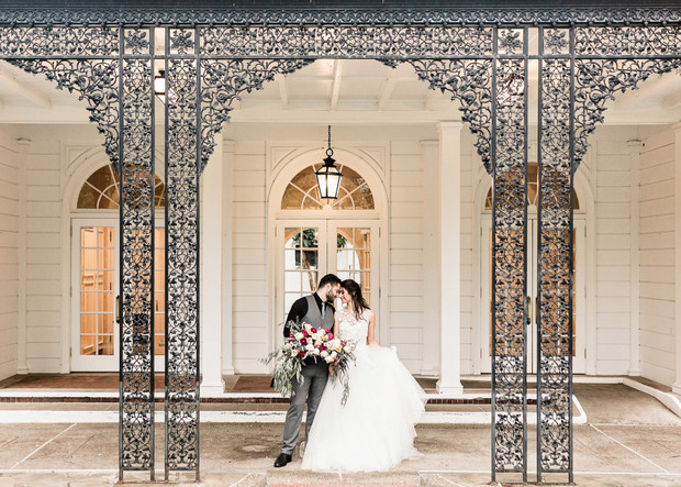 Bride and groom at white building with metal archway