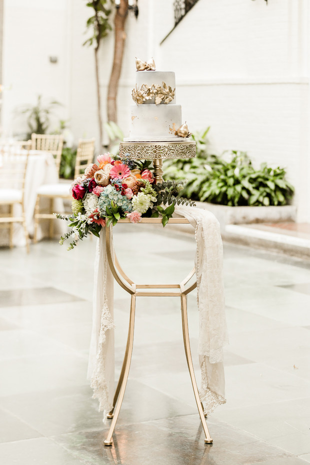 Elegant wedding cake on gold stand with floral decor