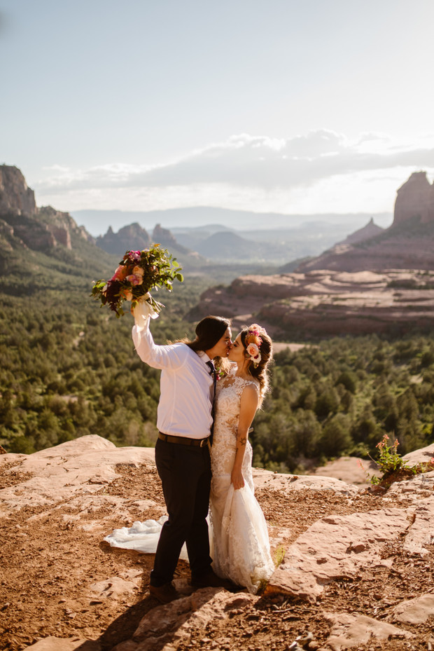 Bride and groom kissing atop scenic mountain vista