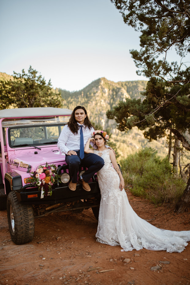 Bride and groom pose on pink Jeep Tours vehicle