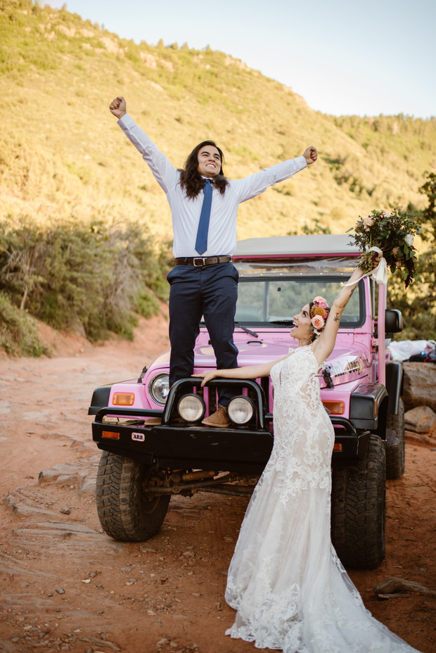 Happy newlyweds celebrating on pink Jeep after wedding