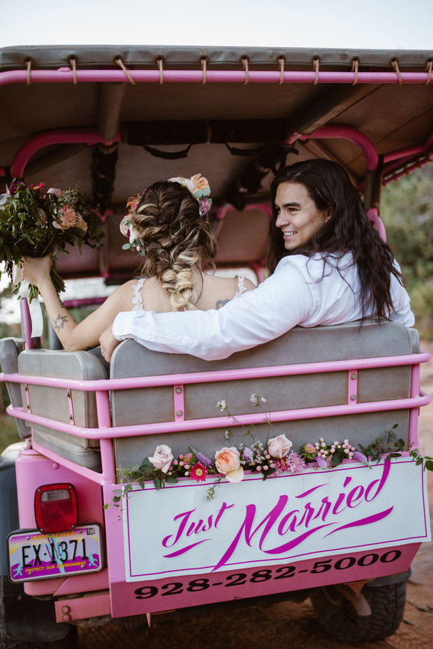 Just married couple ride in pink jeep with Just Married sign