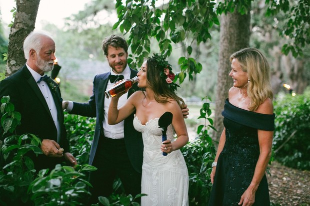 Bride drinking liquor at her wedding with family watching