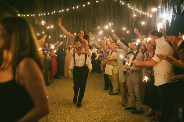 Bride riding groom piggyback with sparkler sendoff