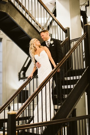 Happy bride and groom on staircase look lovingly at each other