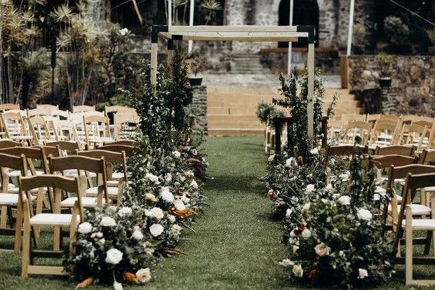 Rustic outdoor wedding ceremony aisle with floral arrangements