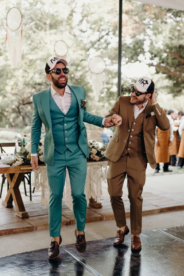 Two grooms joyfully dancing at their outdoor wedding