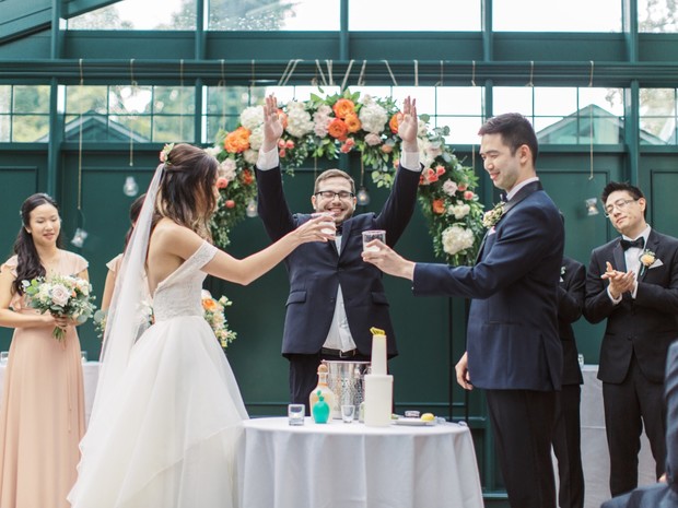 Bride groom and officiant make a toast at their wedding
