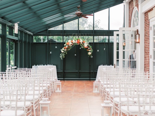 Indoor wedding setup with white chairs and floral arch