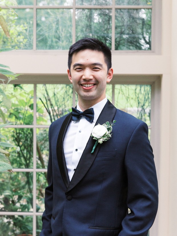Smiling groom in a navy tuxedo with a bow tie outside