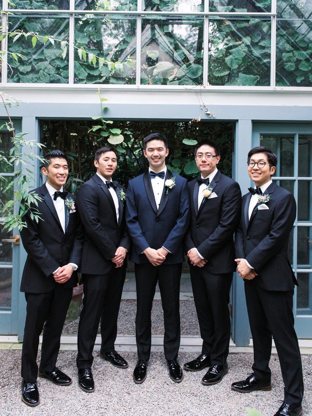 Groomsmen in tuxedos pose at outdoor wedding venue