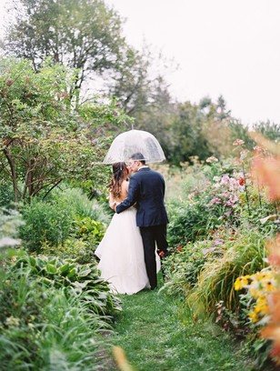 Bride and groom kissing under an umbrella in garden