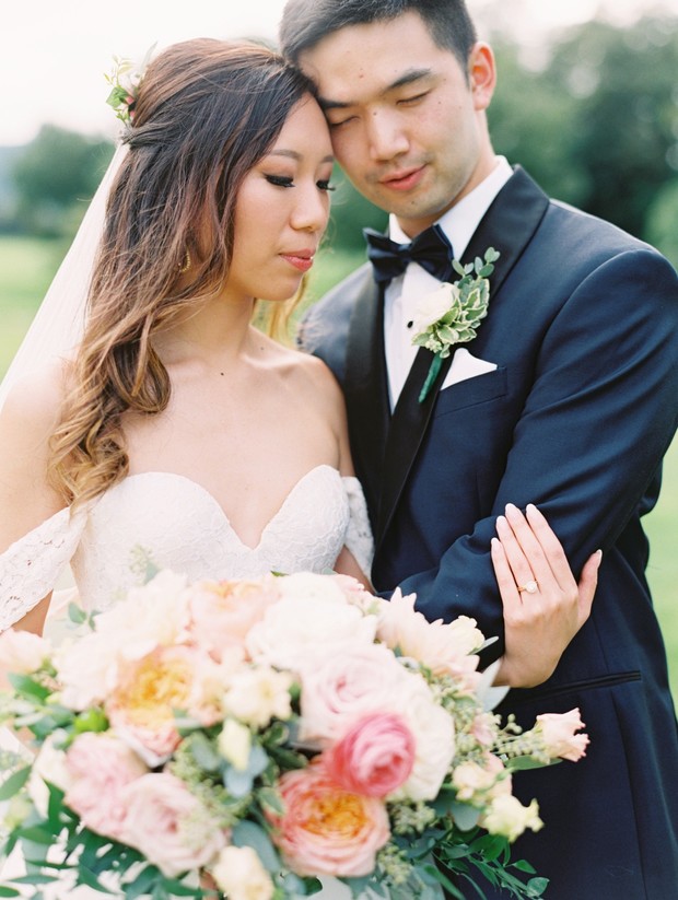 Asian couple embrace on wedding day with floral bouquet