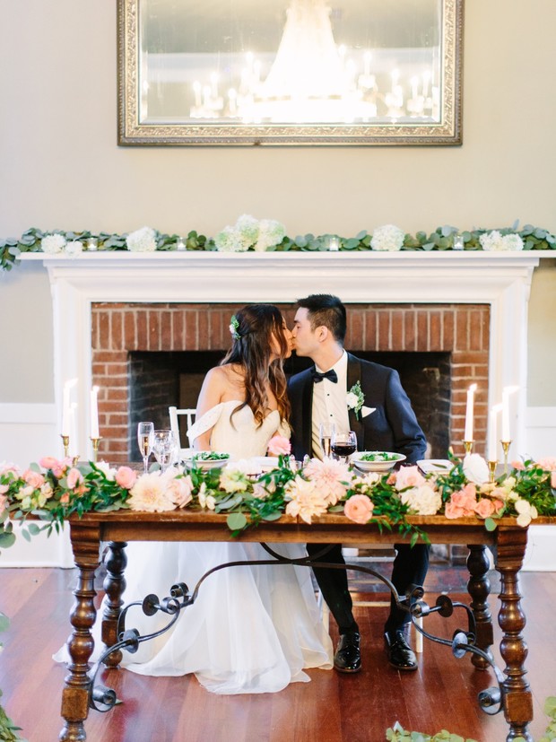 Bride and groom kiss at their romantic wedding table