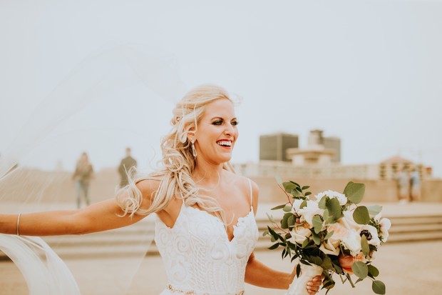 Happy bride laughs holding bouquet at outdoor wedding