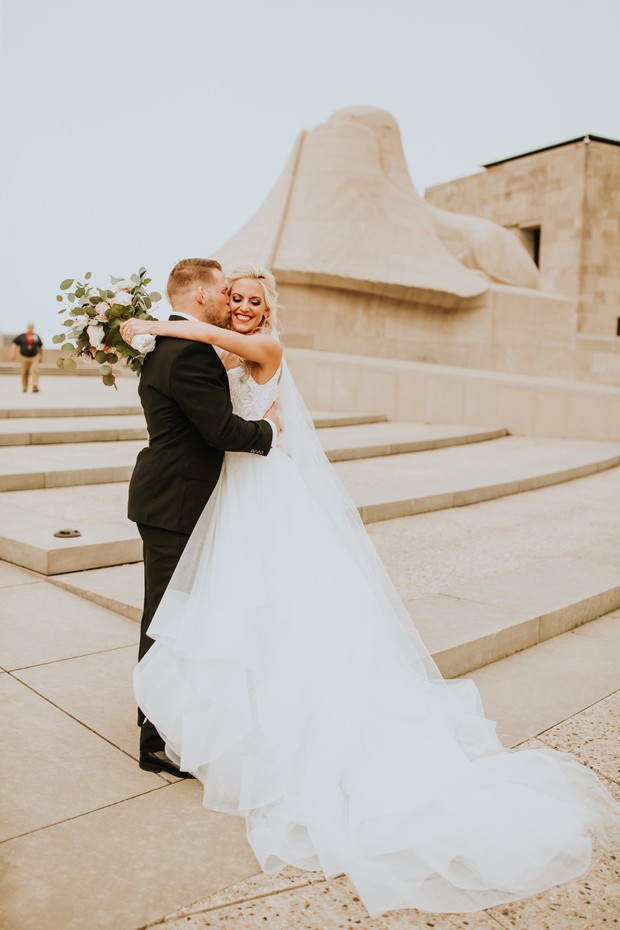Happy couple embrace on wedding day outdoor stone steps