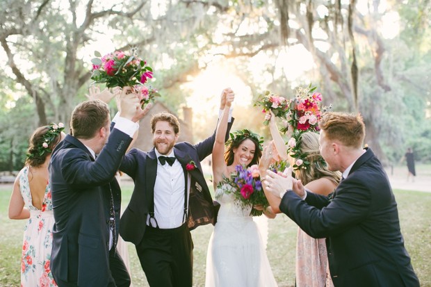 Joyful wedding couple celebrated by guests with flowers