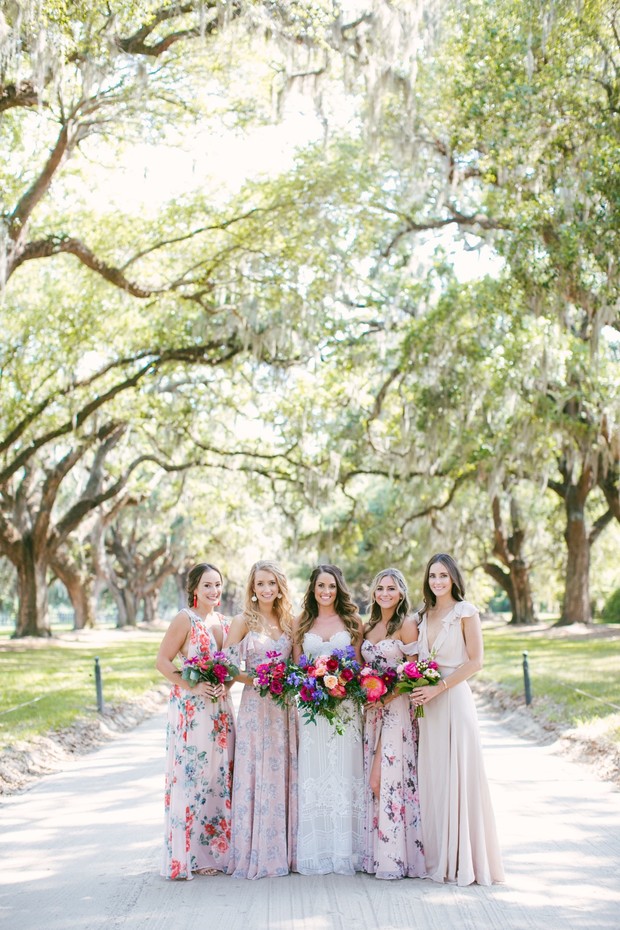 Bride and bridesmaids in floral dresses under oak trees