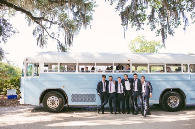 Groomsmen posing by light blue vintage wedding bus