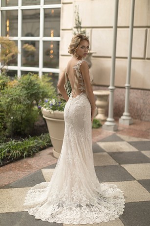 Woman poses in backless lace wedding dress