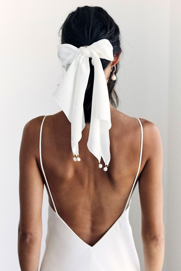 Woman in white backless dress with white silk bow in hair