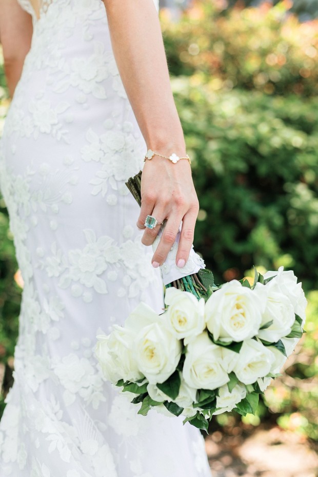 Bride in lace dress with rose bouquet and emerald ring
