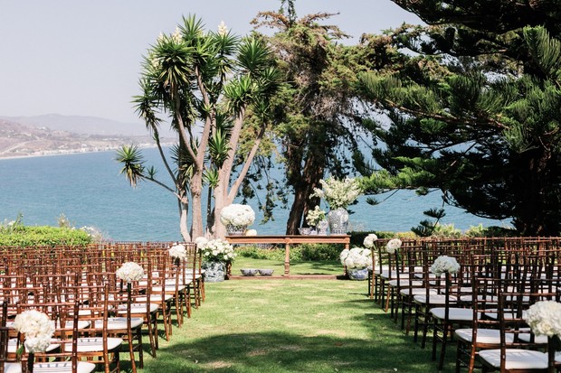 Ocean view wedding setup with white flowers chairs