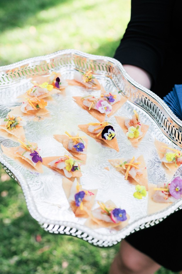 Silver tray holding delicate appetizers topped with edible flowers