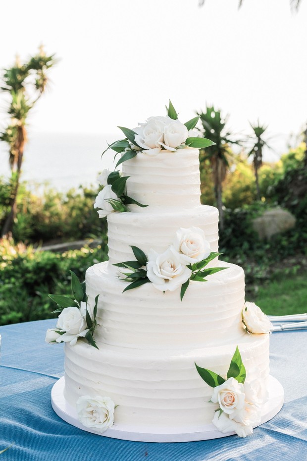 Four tier wedding cake with white frosting and flowers