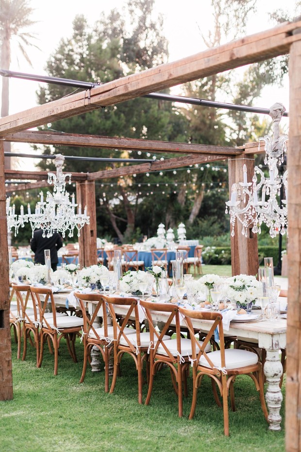 Rustic wedding reception table setting under wooden pergola