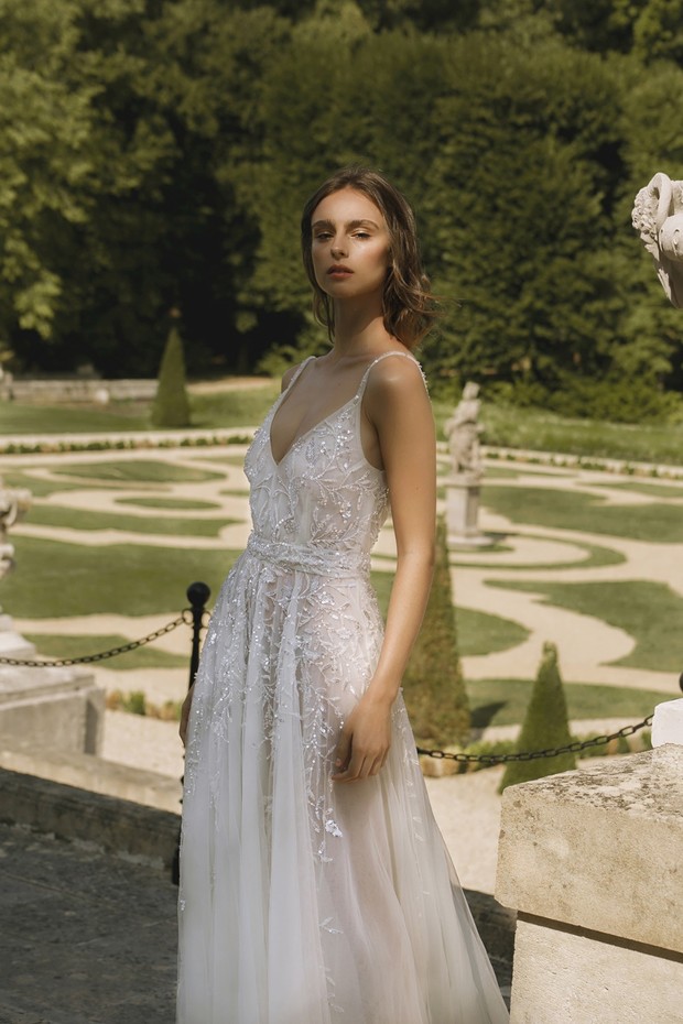Elegant bride in detailed white gown in garden setting