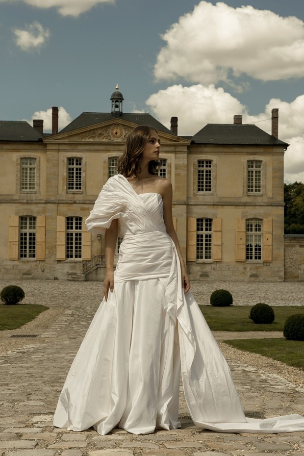 Elegant one-shoulder wedding gown model posing outdoors