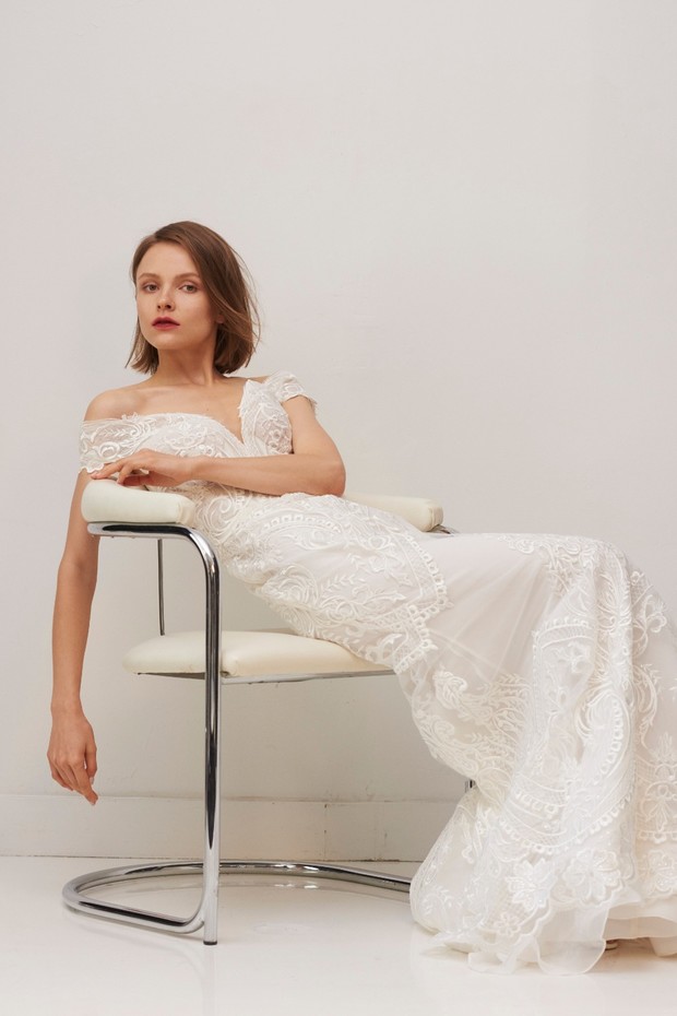 Elegant bride in lace wedding gown sitting on chair