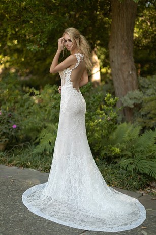 Bride in lace wedding gown with train in garden setting