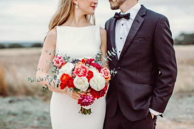 Bride and groom close up portrait with bouquet of flowers