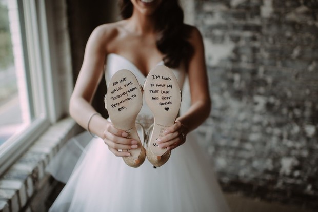 Bride holding wedding shoes with sweet message on the soles