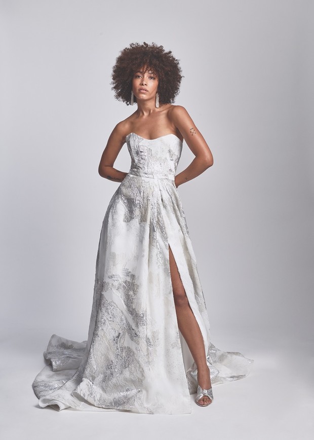 Woman poses in strapless white and silver gown with slit