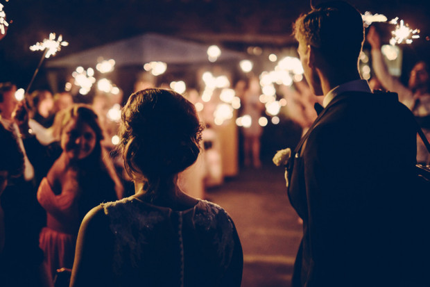 Couple walks through sparklers at their wedding reception celebration