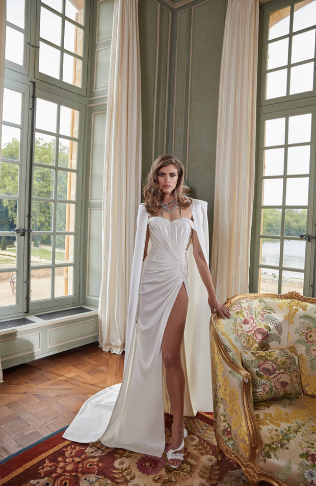 Elegant bride in a white dress with a high slit pose inside a room
