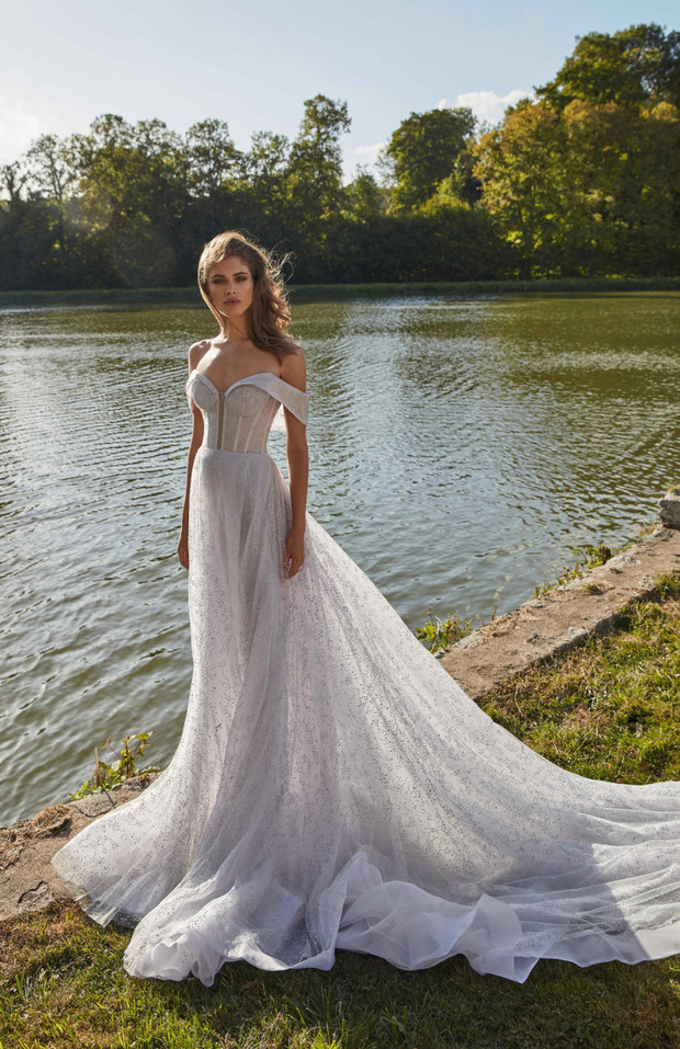 Stunning bride in off-the-shoulder wedding dress near the lake