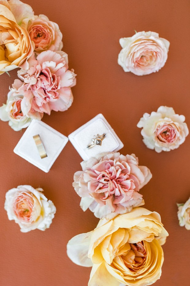 Wedding rings in white boxes surrounded by peach flowers