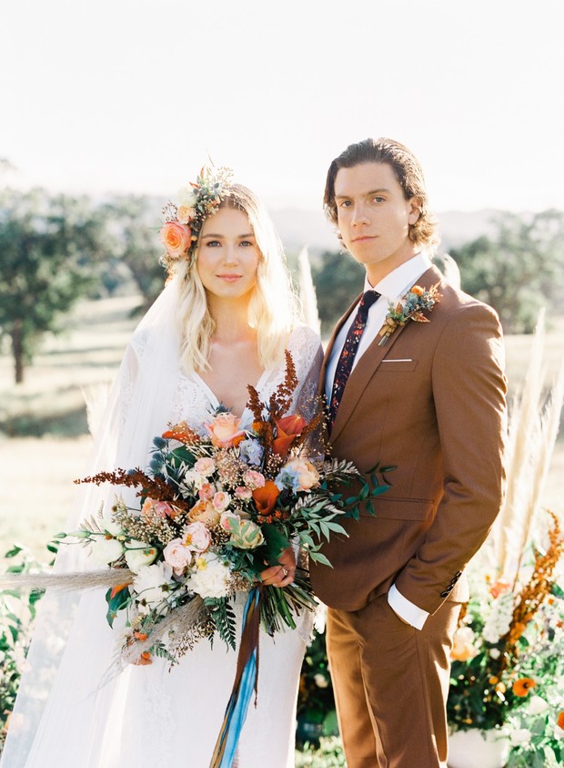 Boho chic wedding couple outdoors with floral accents