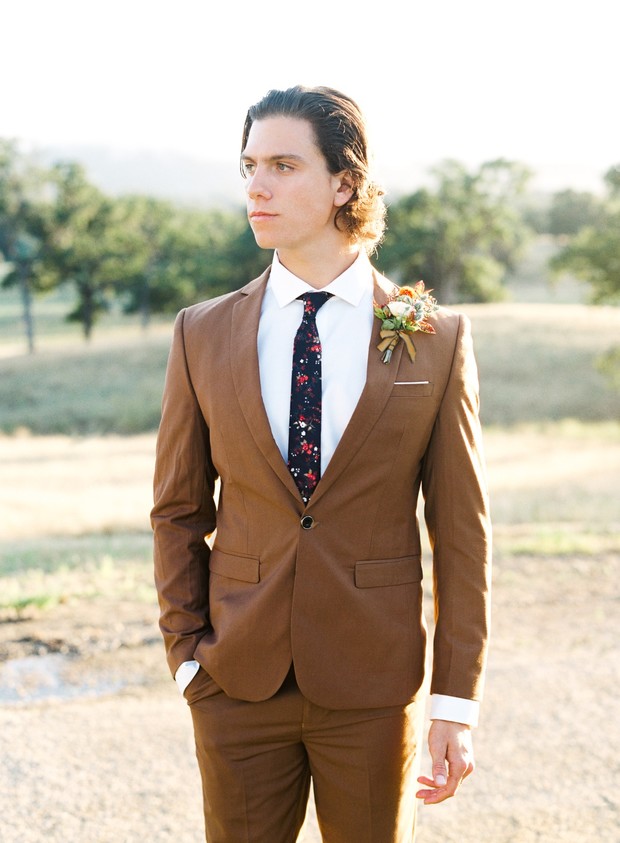 Groom in a stylish brown suit with floral tie outdoors