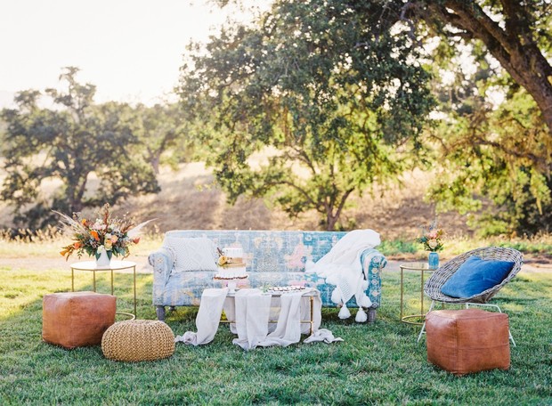 Rustic outdoor lounge with patterned sofa, treats, and poufs