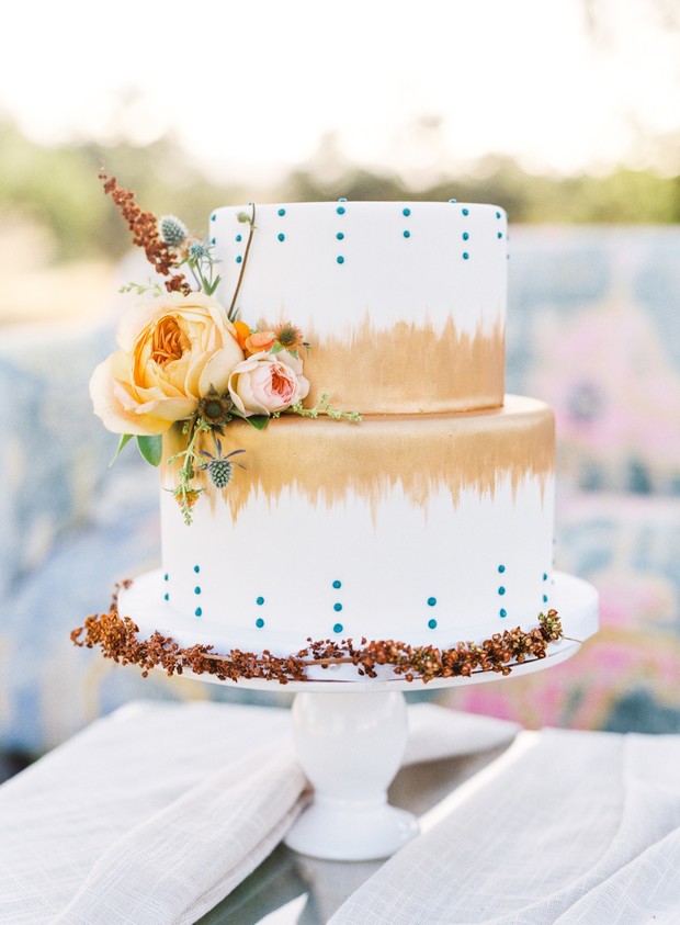 Elegant two-tiered wedding cake with gold and teal accents