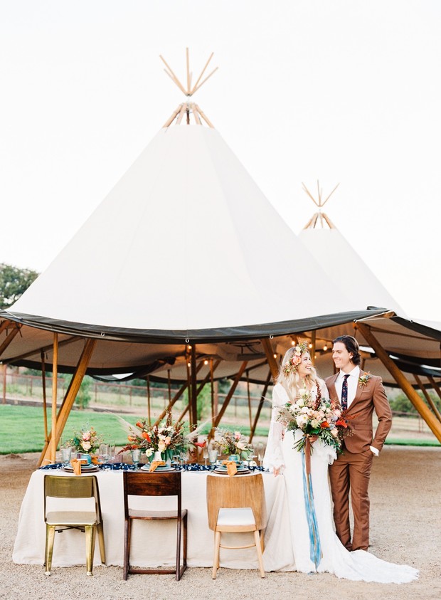 Couple posing at rustic wedding reception under teepee