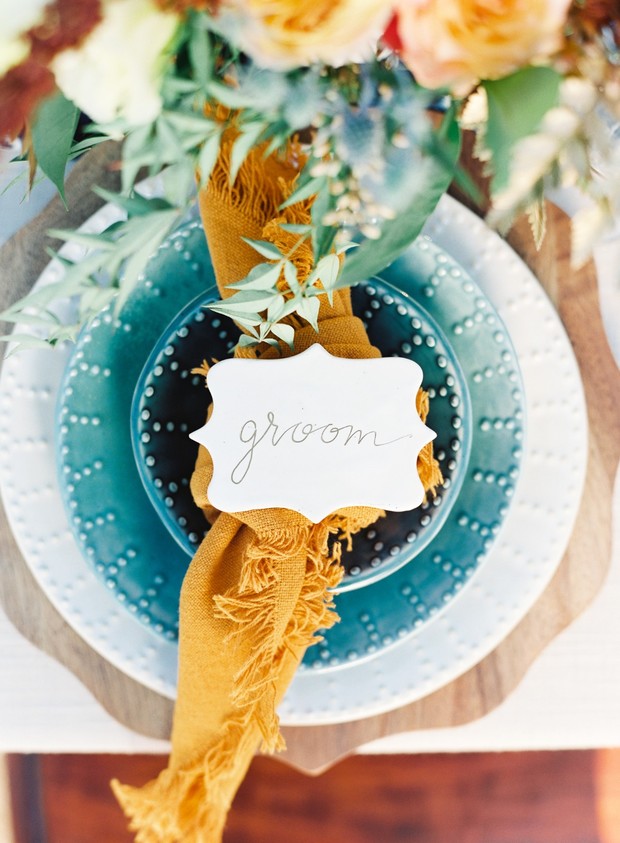 Elegant groom place setting with teal plates and marigold napkin