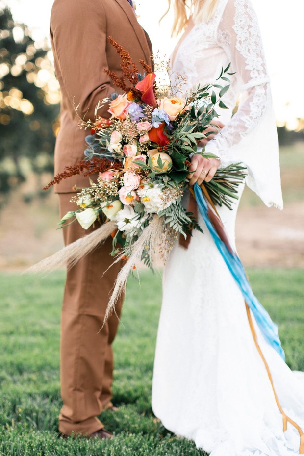 Bride holding boho wedding bouquet with colorful ribbons