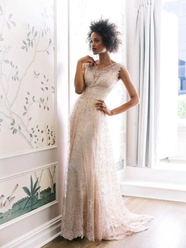Woman in elegant lace wedding dress posing indoors