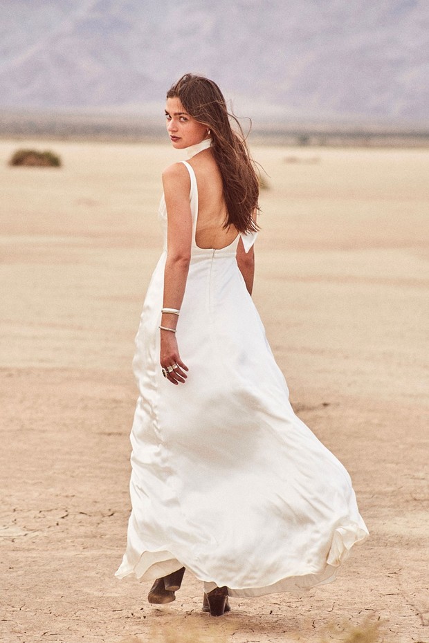Woman in white dress and boots walks in the desert